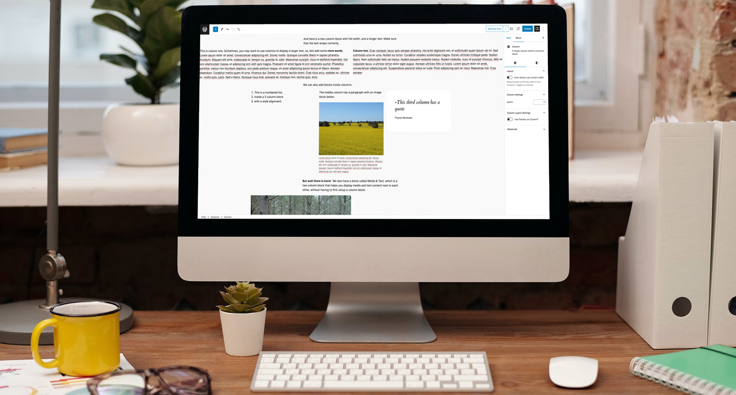 an iMac on a desk with a keyboard and notebooks showing the WordPress block editor with columns blocks